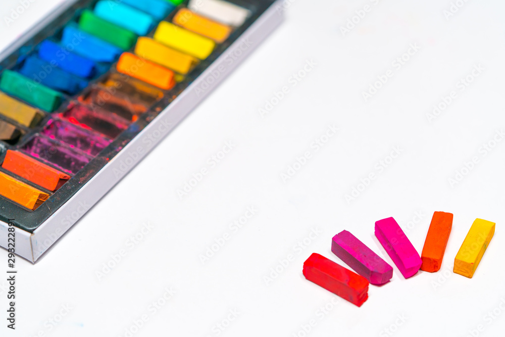 pastel art materials, crayons of different colors in a box and on a table on a white paper background pastel art materials, crayons of different colors in a box and on a table on a white paper background