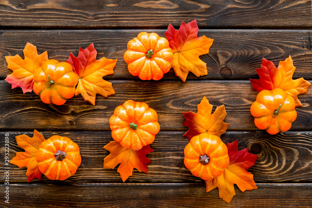 Autumn composition. Pattern with red and orange leaves and pumpkins on dark wooden background top view