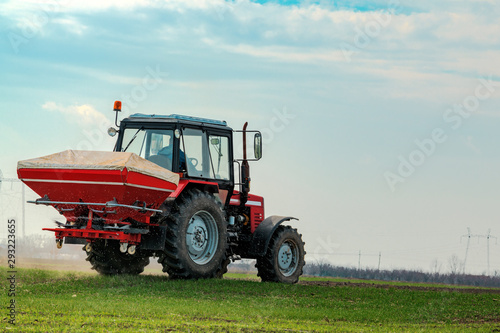 Agricultural tractor fertilizing wheat crop field with NPK