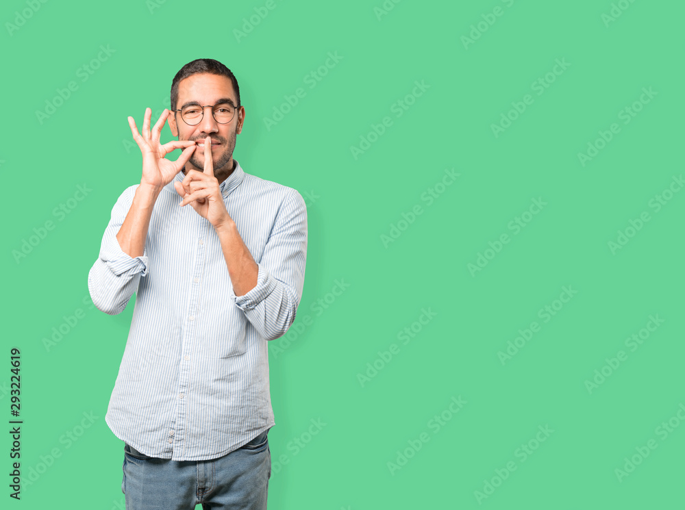 Happy young man asking for silence gesturing with his finger Happy young man asking for silence gesturing with his finger