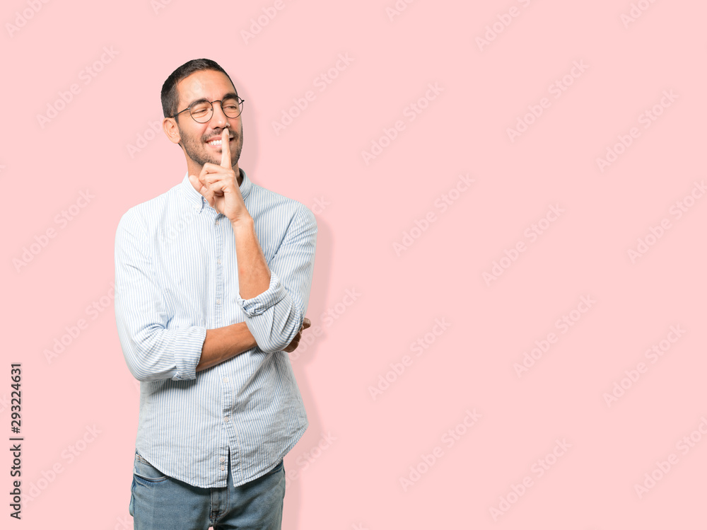 Happy young man asking for silence gesturing with his finger Happy young man asking for silence gesturing with his finger