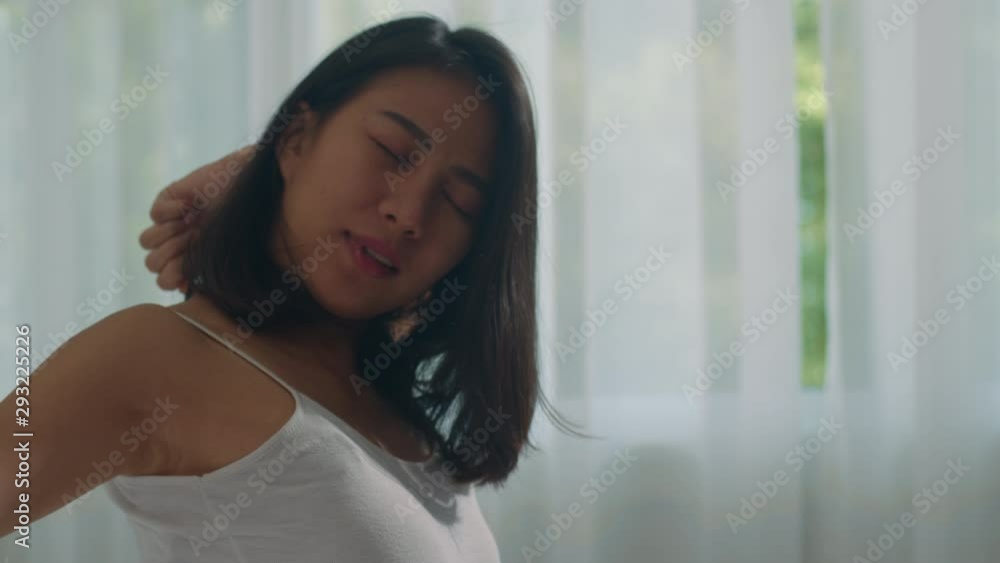 Teen hispanic woman wakes up at home. Young Asian girl stretching after awake sleep all night starting a new day with energy and vitality felt very refreshed on bed near window in bedroom at morning. Teen hispanic woman wakes up at home. Young Asian girl stretching after awake sleep all night starting a new day with energy and vitality felt very refreshed on bed near window in bedroom at morning.