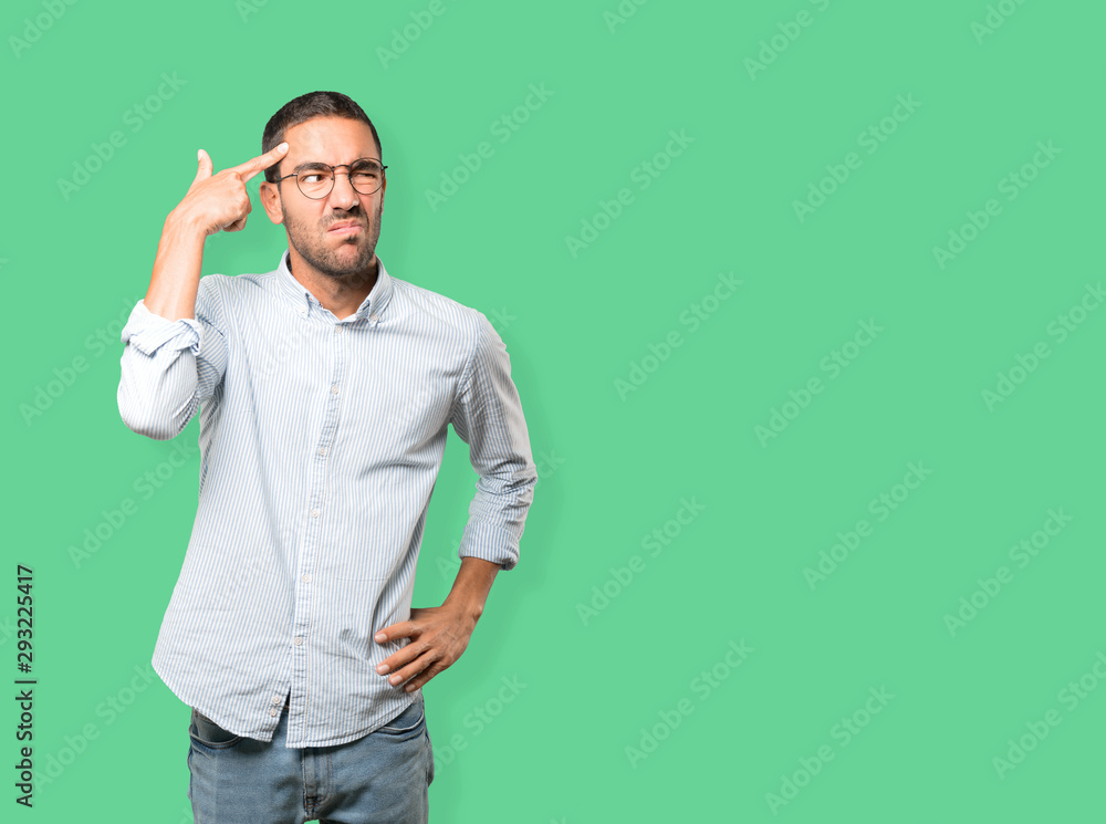 Depressed young man making a suicide gesture Depressed young man making a suicide gesture