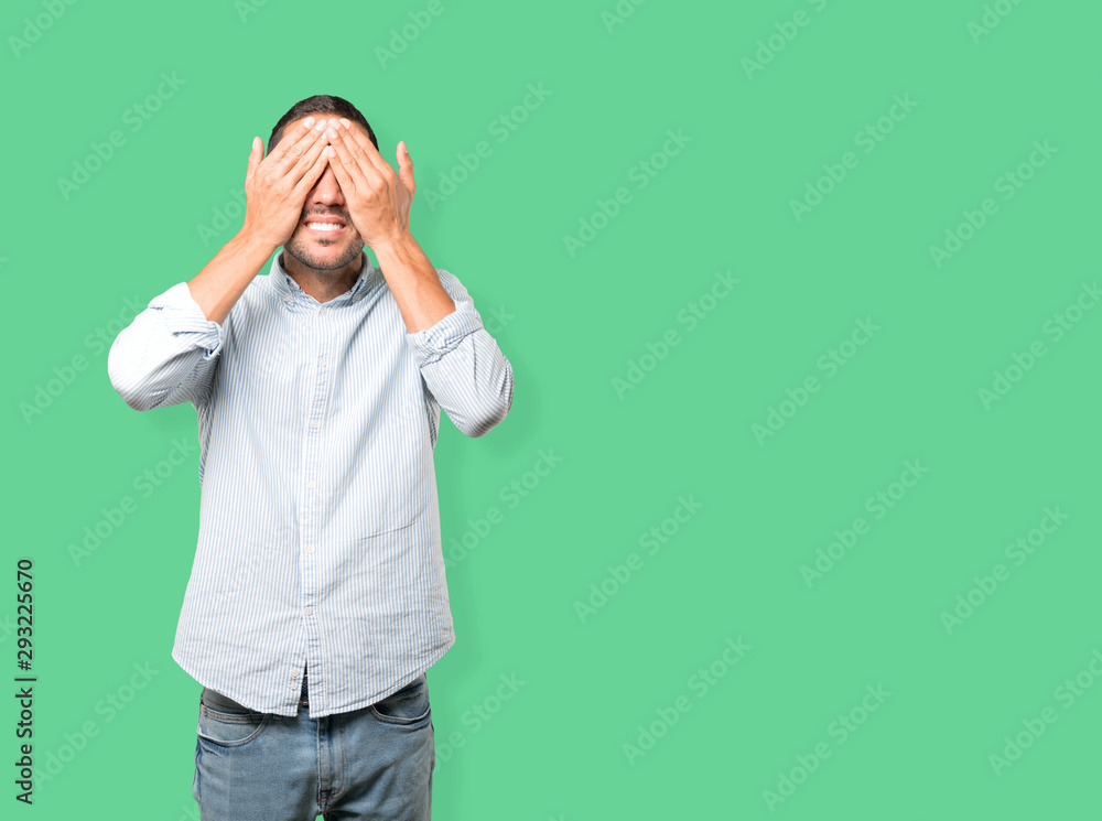 Young man covering his eyes with his hands Young man covering his eyes with his hands