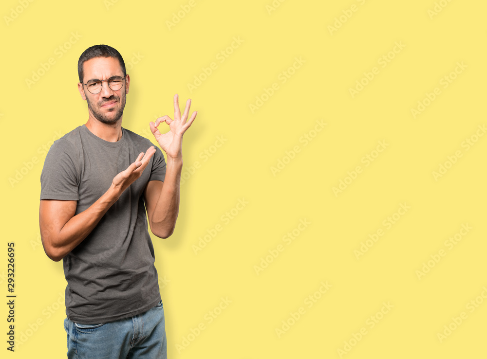 Worried young man doubting and making a gesture of approval Worried young man doubting and making a gesture of approval