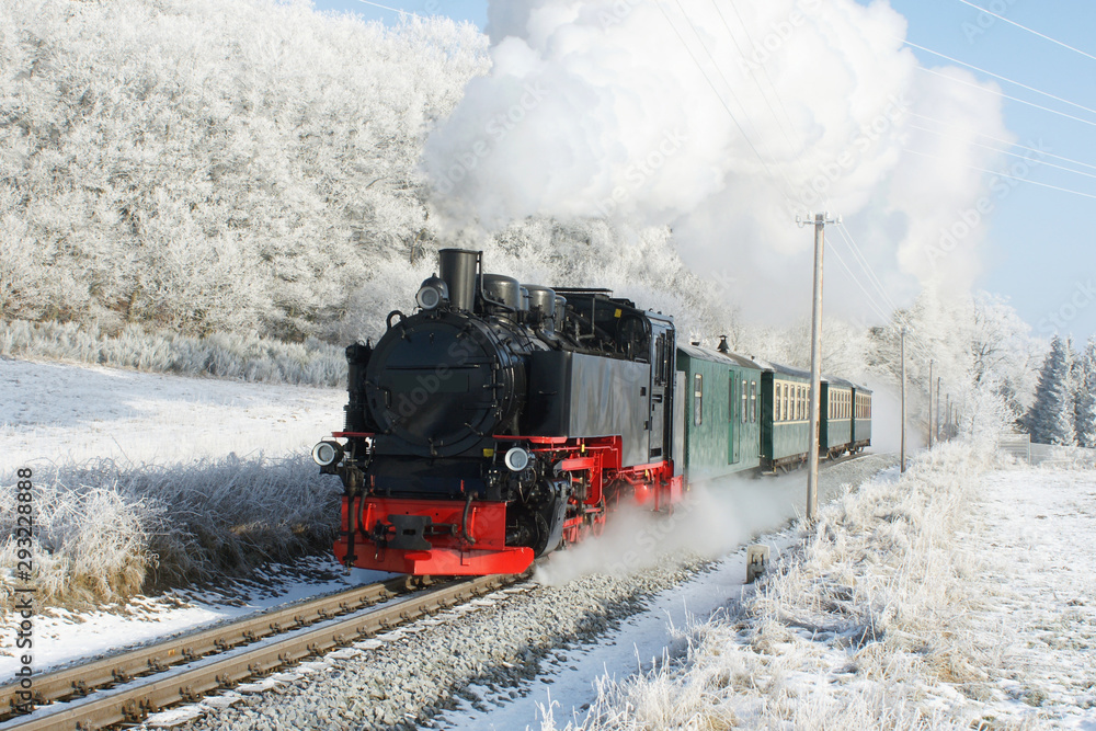 Obraz premium Lokomotywa parowa przed pociągiem pasażerskim zimą z dużą ilością pary