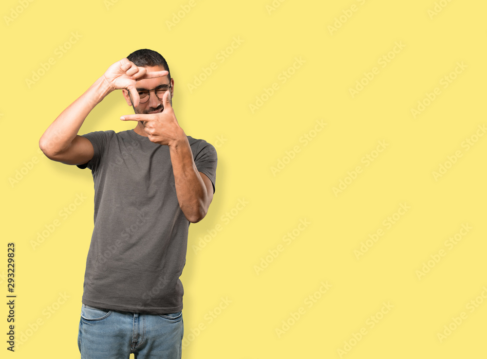 Friendly young man making a gesture of taking a photo with the hands Friendly young man making a gesture of taking a photo with the hands