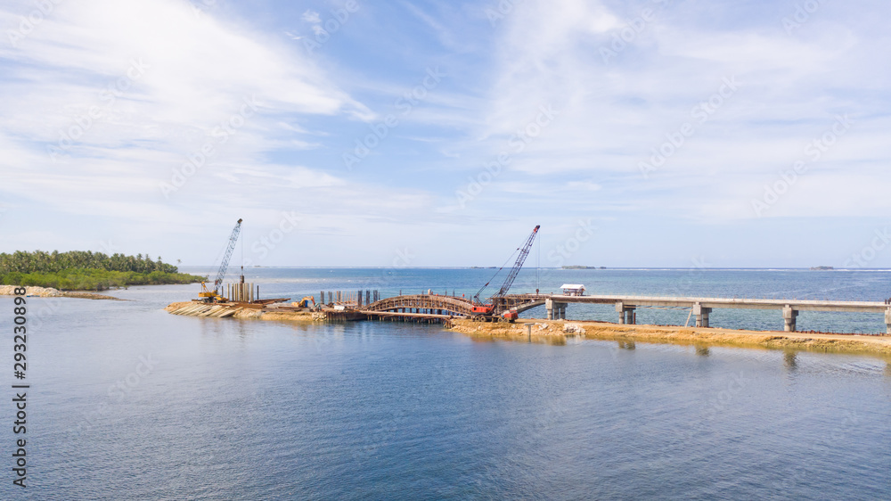 Construction of a bridge across the bay. Construction equipment on the bridge, top view. New bridge on the island of Siargao, Philippines.