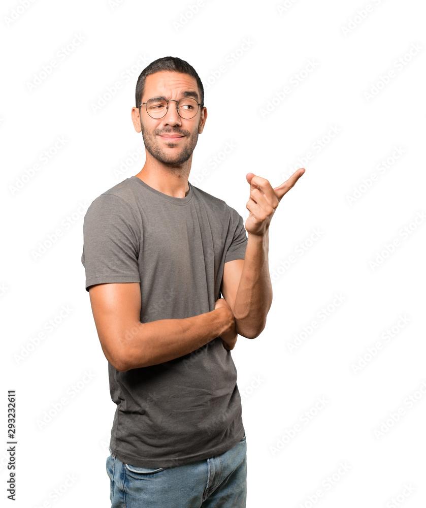 Hesitant young man pointing at you with his finger Hesitant young man pointing at you with his finger