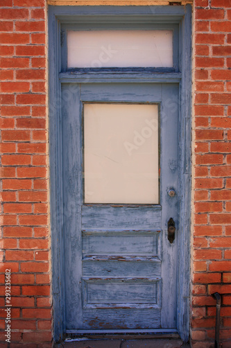 Distressed grey painted door set back in a red brick building doorway