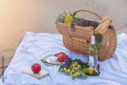 Fototapeta Naklejka Na Ścianę i Meble -  Basket with fruits apples, pears, grapes, bread, glasses and wine, picnics on the seashore, picnic basket  in the sand
