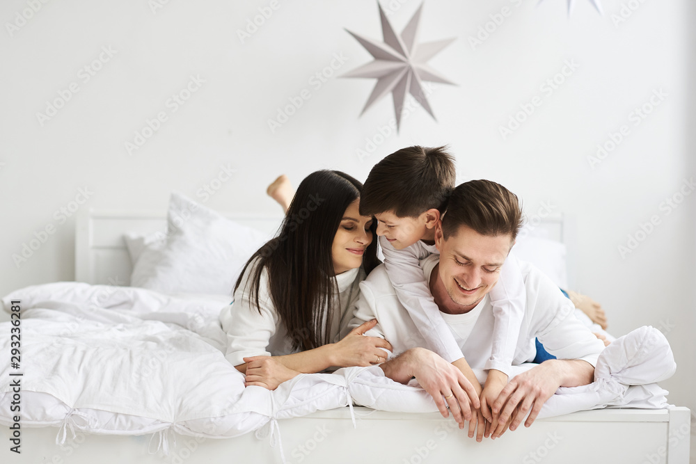 A beautiful young family in the morning bedroomis relaxing and have a fun on a white background A beautiful young family in the morning bedroomis relaxing and have a fun on a white background
