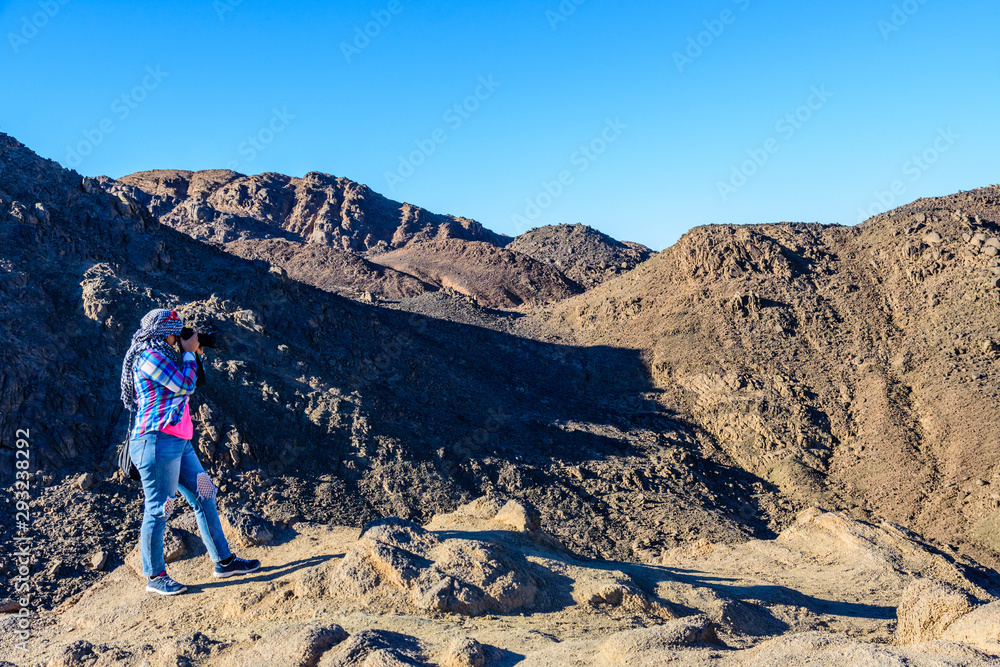 Young woman taking a photo in Arabian desert not far from the Hurghada city, Egypt