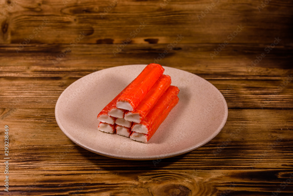 Ceramic plate with pile of crab sticks on a wooden table Ceramic plate with pile of crab sticks on a wooden table
