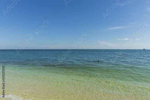 Beautiful view of Atlantic ocean.  Blue water surface merging with light blue sky in horizon line. One person is swimming. Key West, Florida. USA 