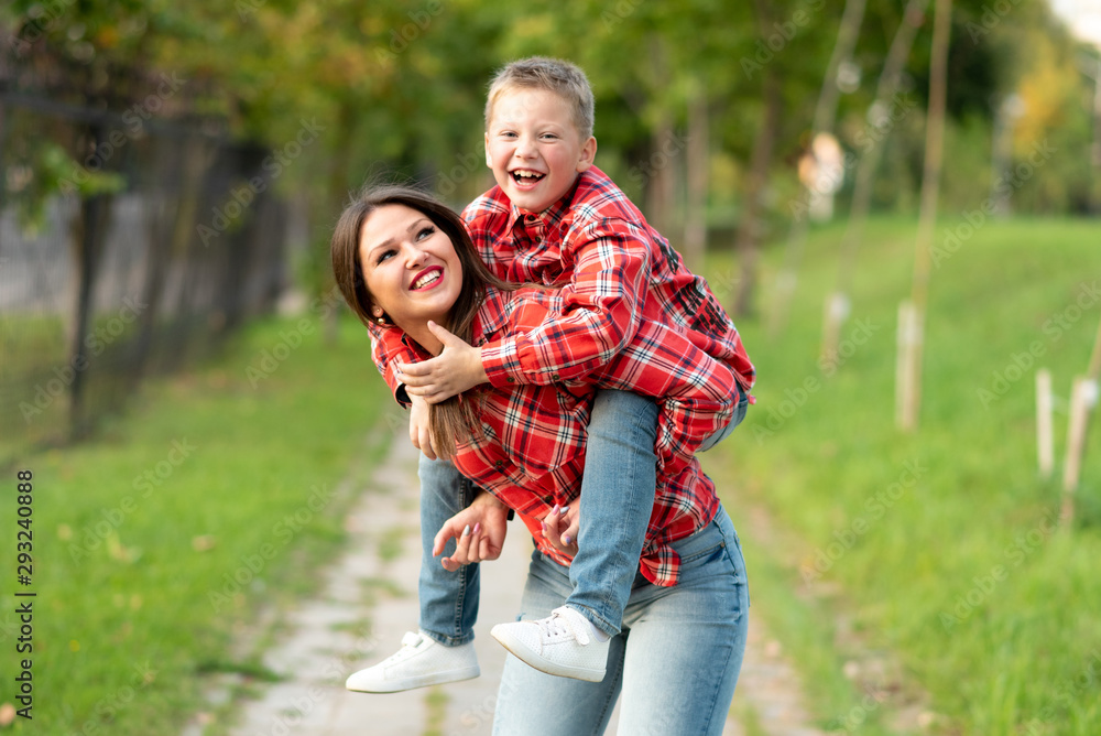 Fototapeta premium Mom, laughing, holds on his back a laughing son.