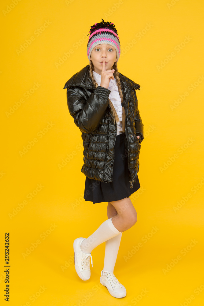 Keep secret. Fashion shop. Girl wear knitted hat and down jacket yellow background. Fashion concept. Warm clothing. Buy clothes for school season. Schoolgirl fashion outfit. Fall autumn winter