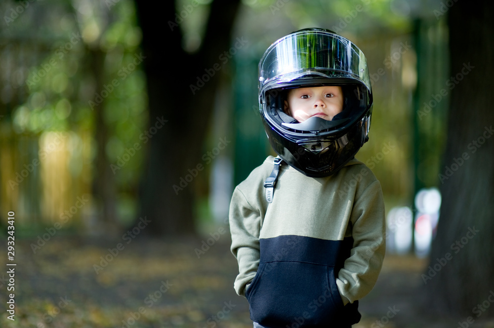funny kid with a big motorcycle helmet on his head. Stock Photo | Adobe  Stock