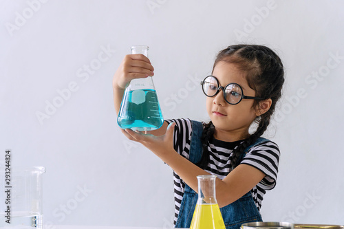 Little 6s cute girl with microscope holding laboratory bottle with water experiment study scientists at school. Education science concept.