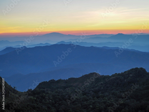 Beautifully graded twilight at Chiang Dao Mountain, the horizon line is orange. Many mountains are dark blue and light.