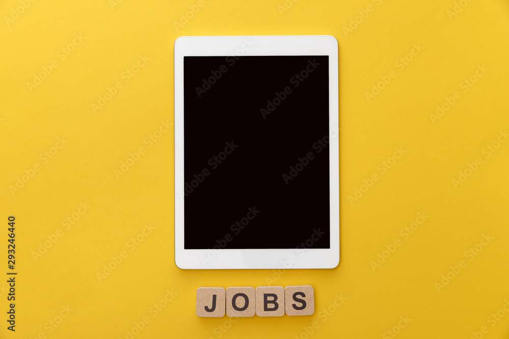 top view of digital tablet with blank screen and cardboard squares with jobs inscription on yellow background top view of digital tablet with blank screen and cardboard squares with jobs inscription on yellow background