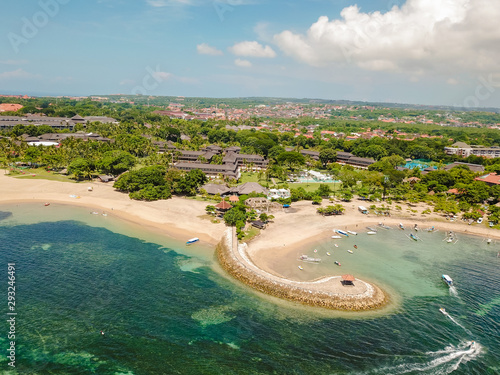 Bay of Nusa Dua beach in Bali Indonesia viewed from above during summer day with drone flying over the  resort area in the peak of the tourist season photo
