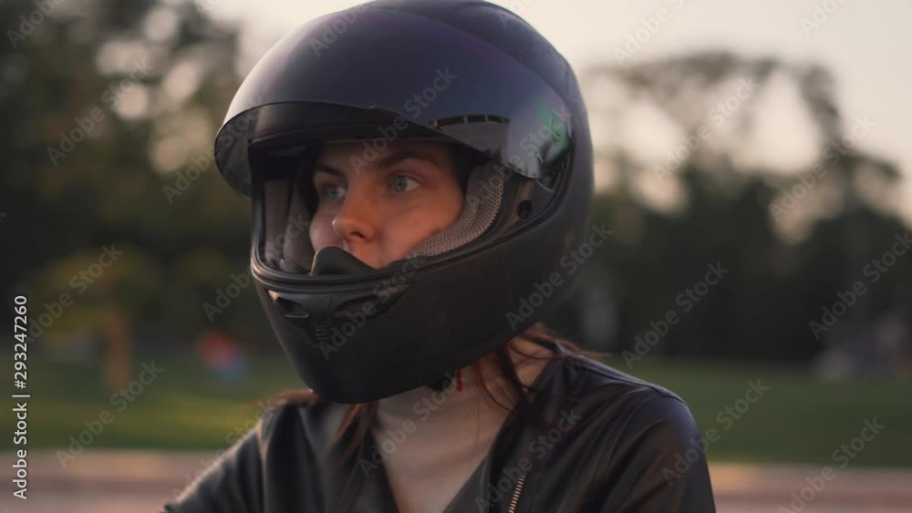 Beautiful young red-haired woman motorcyclist sitting on custom bike with black motorcycle helmet Beautiful young red-haired woman motorcyclist sitting on custom bike with black motorcycle helmet