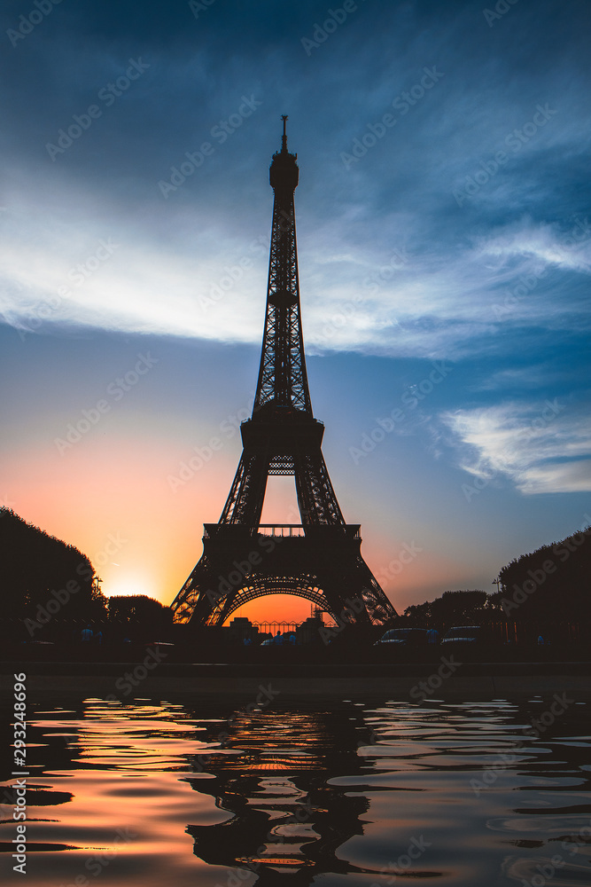 Naklejka premium The Eiffel Tower, reflected in the water at sunset, a landmark of the Paris capital of France constructed of steel in the 19th century.