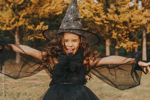 Fototapeta Cute girl in costume of witch on nature background