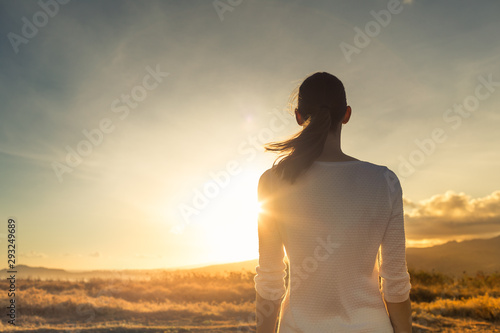 Life is beautiful. Woman standing facing a beautiful golden sunrise.  photo