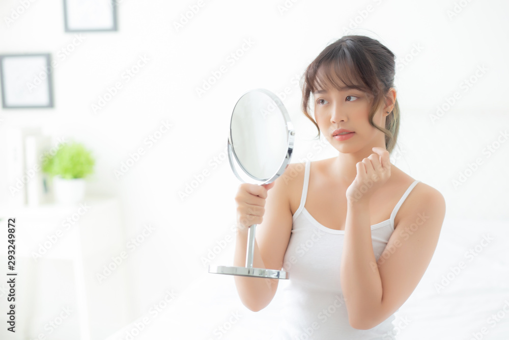 Beautiful young asian woman looking the mirror with acne problem at bedroom, trouble of beauty on face, zit treatment, asia girl is pimple having worry and displeased, skincare and healthy concept. Beautiful young asian woman looking the mirror with acne problem at bedroom, trouble of beauty on face, zit treatment, asia girl is pimple having worry and displeased, skincare and healthy concept.