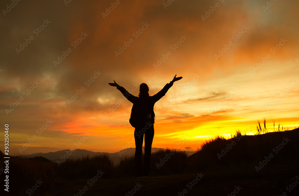Hiker on a mountain facing the sunset view feeling free and happy. 