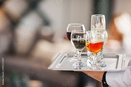 Waiter serving glasses of cold beer, soft drinks and white wine on the tray at a business meeting