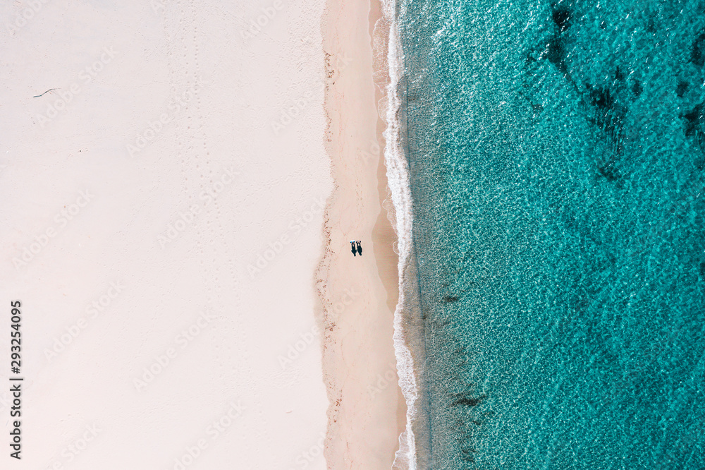 Aerial view on the couple walking on the beautiful beach on Sardegna Italy