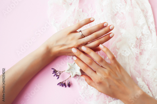 woman hands with manicure and wedding ring among white lace and little flowers