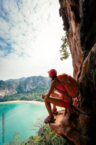 Young woman backpacker hiking on seaside mountain top,sit on cliff edge enjoy the view