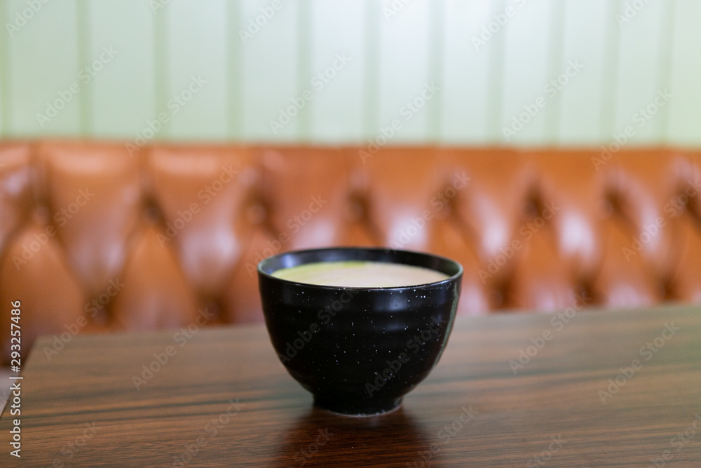 Golden milk matcha latte with turmeric, on coffee shop table, leather chair and green wall in background, copy space Golden milk matcha latte with turmeric, on coffee shop table, leather chair and green wall in background, copy space