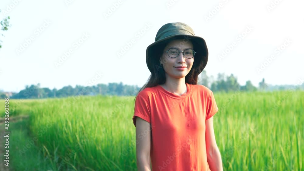 Asian woman in orange shirt looking at green rice field. Asian woman in orange shirt looking at green rice field.