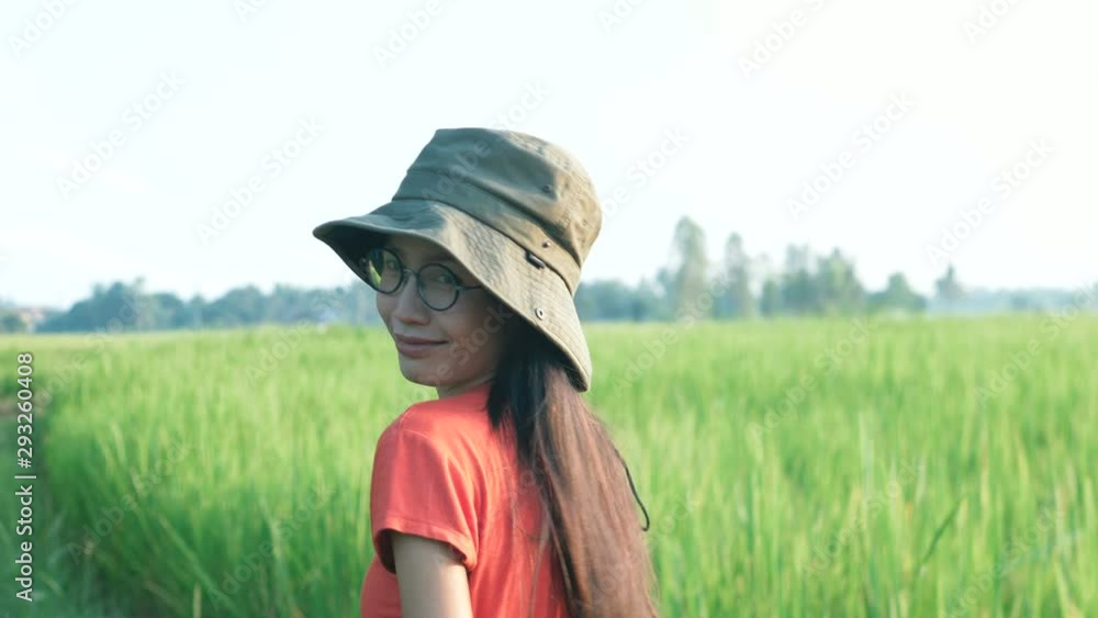 Asian woman in orange shirt looking at green rice field. Asian woman in orange shirt looking at green rice field.