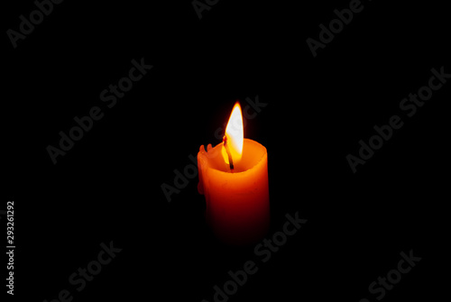 A stearin candle burning in total darkness as the only source of light
