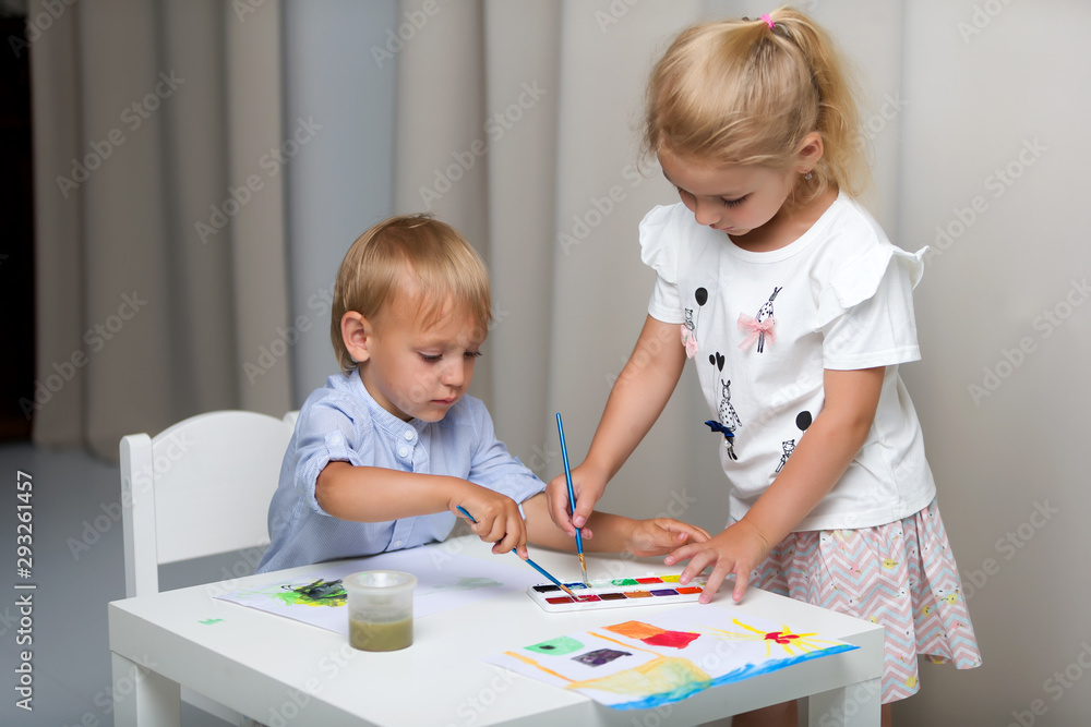 Brother and sister, girl and boy paint with watercolors at the t Brother and sister, girl and boy paint with watercolors at the t