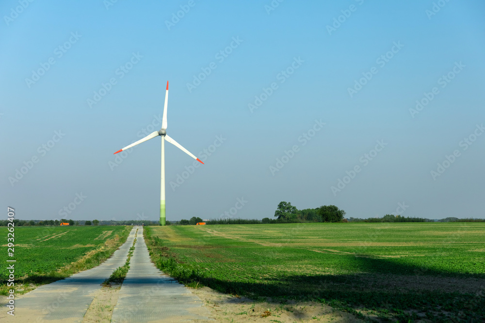 Obraz premium wind generators on a green field under a blue sky on a bright sunny day