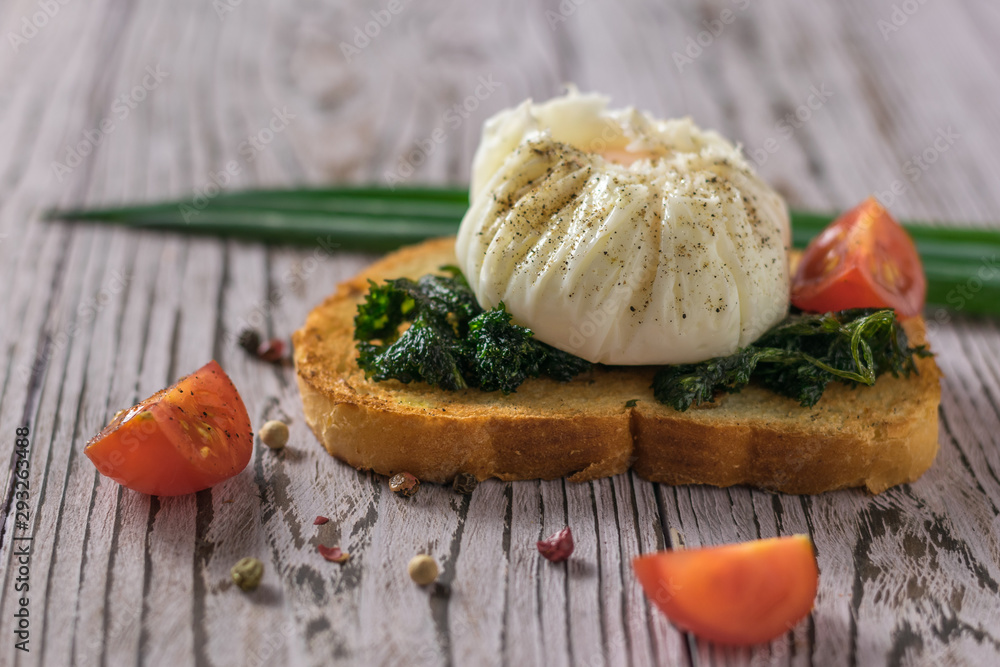 Poached egg on a piece of bread and tomato slices on a wooden table. Poached egg on a piece of bread and tomato slices on a wooden table.