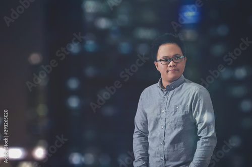 Night scene of a man standing and thinking about something, man in long sleeves and with eye glasses. Guy looking at something at the right side of his room. Awake at midnight concept. 