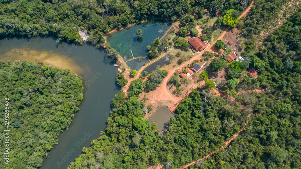 Aerial view of an meandering Amazon tributary river and buildings in the Amazonian rainforest, Mato Grosso, Brazil