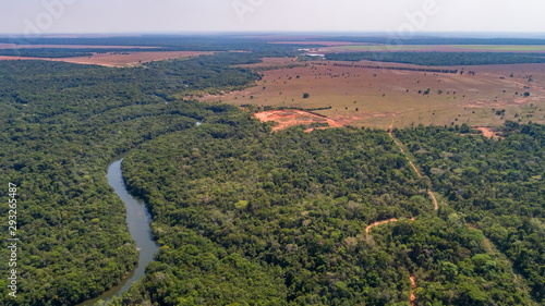 Aerial view of a meandering Amazon tributary river, roads through rainforest and bordering agricultural land, Amazonian rainforest, San Jose do Rio Claro, Mato Grosso