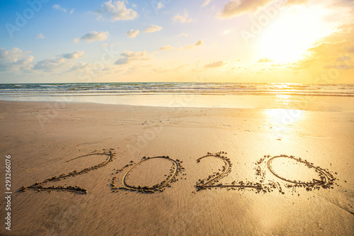 Happy New Year 2020 text on beautiful the sea beach with wave early morning sunrise over the horizon background.During Christmas and New Year.