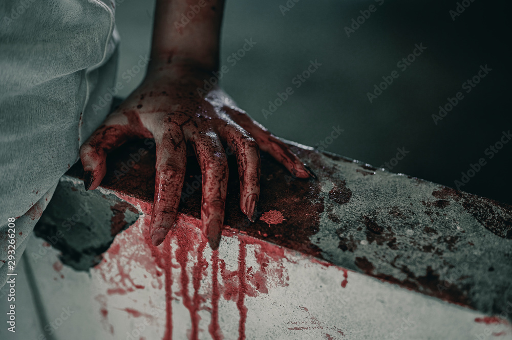 Horror Scene of a Woman with bloody hands sitting in abandoned building, Halloween murder concept.