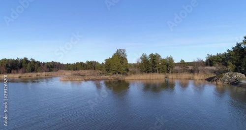 Aerial drone shot of calm, remote and wild lake Vaenern in the south of Sweden in autumn with swamp, coniferous trees and rocks at sunshine. photo