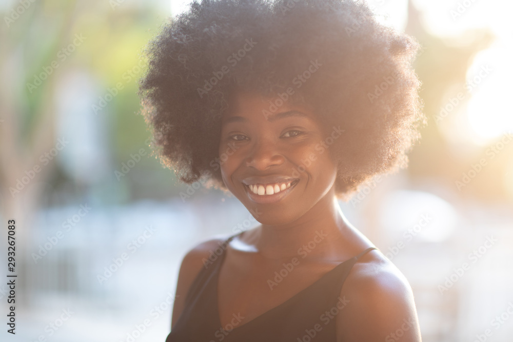 Portrait of smiling young black woman with sunlight flare and copy space Portrait of smiling young black woman with sunlight flare and copy space
